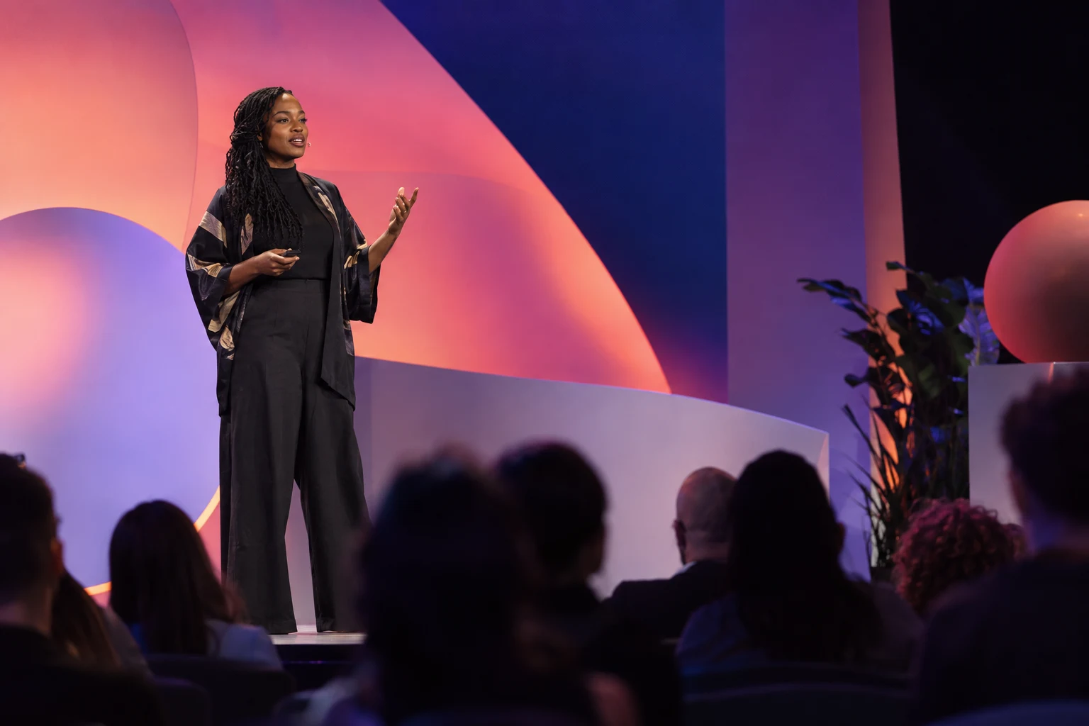 Speaker on a vivid geometric stage before a seated conference audience